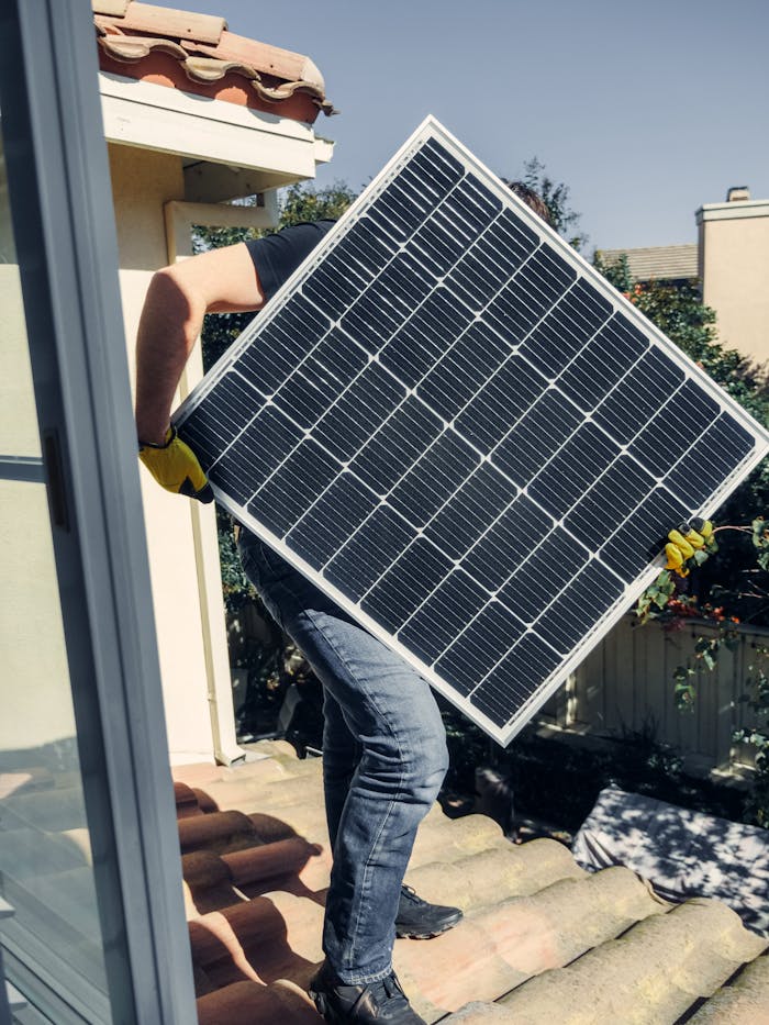 story-02 A worker carrying a solar panel for installation on a sunlit rooftop, showcasing clean energy.